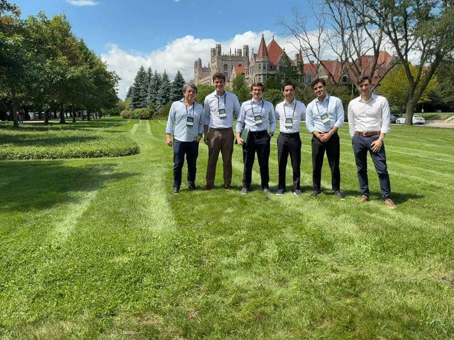 Grupo de consultores da Nord posados no campus gramado da University of Chicago, com prédio histórico ao fundo